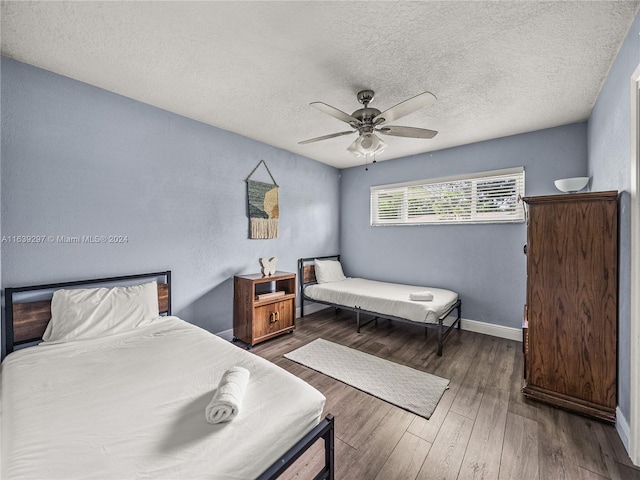 bedroom with ceiling fan, dark hardwood / wood-style flooring, and a textured ceiling