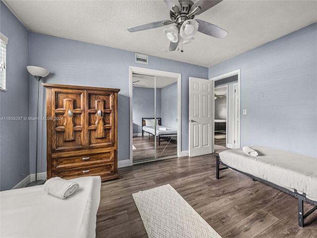 bedroom with a closet, a textured ceiling, dark hardwood / wood-style flooring, and ceiling fan