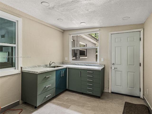 interior space with sink, a textured ceiling, light tile patterned floors, and green cabinets