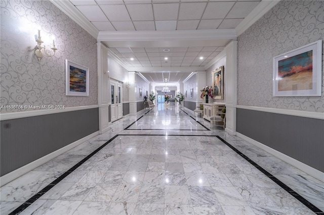 corridor with ornamental molding, a paneled ceiling, and an inviting chandelier