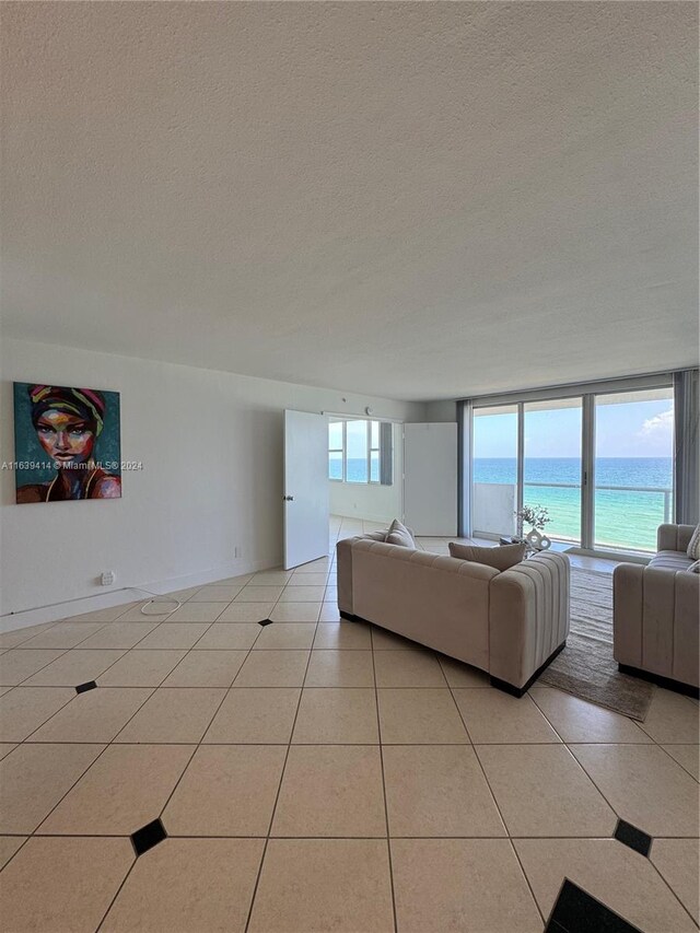 9195 Collins Ave Unit 801, Surfside, FL 33154 - living area featuring a textured ceiling, a water view, and light tile patterned floors