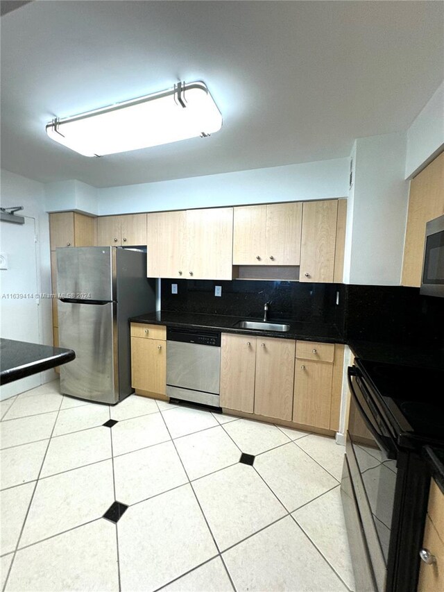 9195 Collins Ave Unit 801, Surfside, FL 33154 - kitchen with appliances with stainless steel finishes, dark countertops, a sink, light tile patterned floors, and light brown cabinets