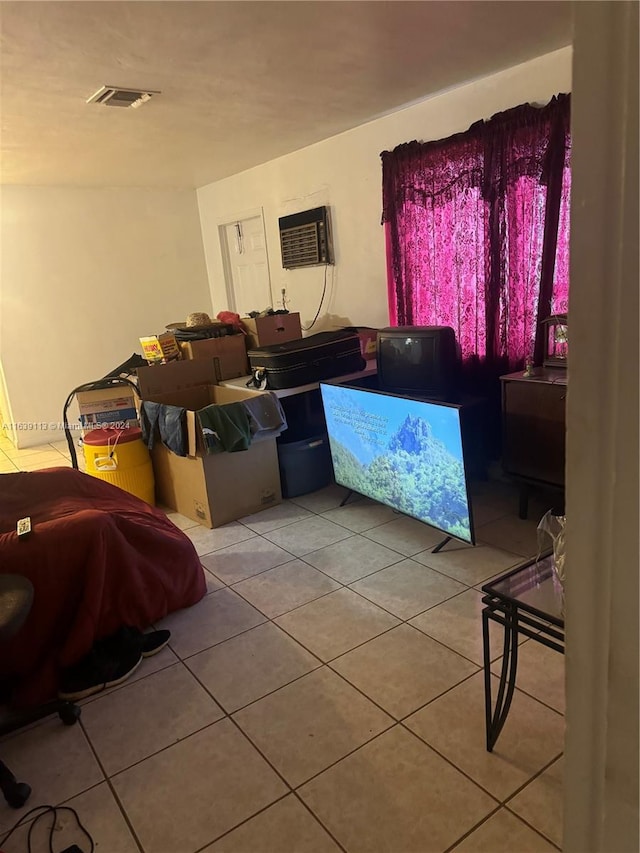 living room with a wall unit AC, visible vents, and tile patterned floors