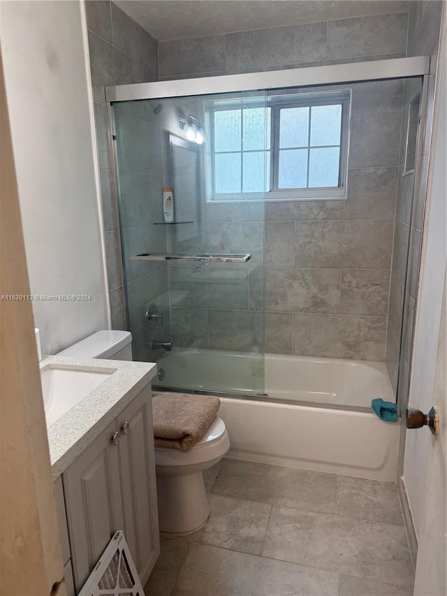 full bathroom with combined bath / shower with glass door, vanity, and toilet