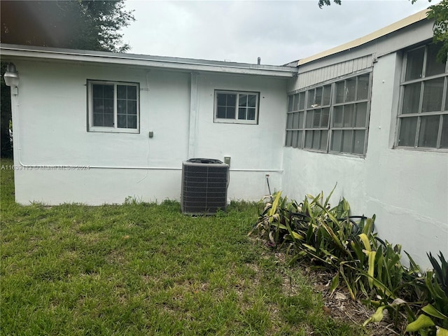 view of property exterior with central AC and a yard