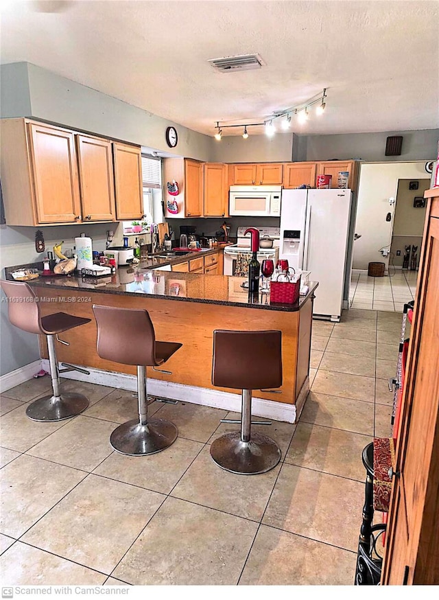 kitchen featuring white appliances, rail lighting, kitchen peninsula, and light tile patterned floors