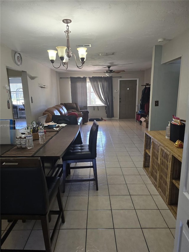 tiled dining room featuring ceiling fan with notable chandelier