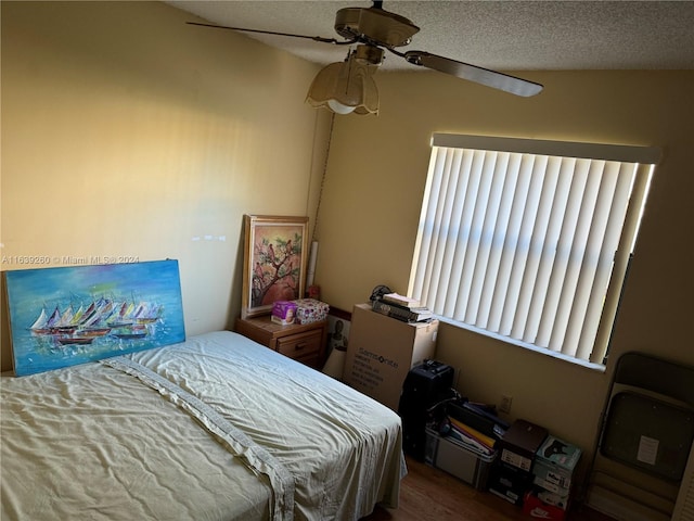 bedroom featuring ceiling fan, wood-type flooring, and a textured ceiling