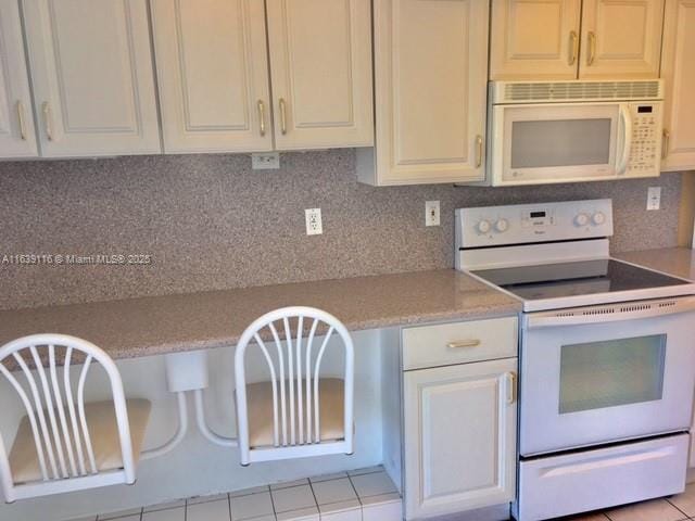 kitchen with light tile patterned flooring, decorative backsplash, and white appliances