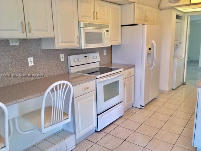 kitchen featuring white cabinets, light tile patterned floors, decorative backsplash, and white appliances