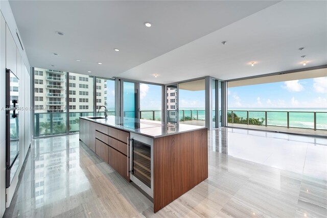 kitchen featuring a water view, wine cooler, a wall of windows, and a spacious island