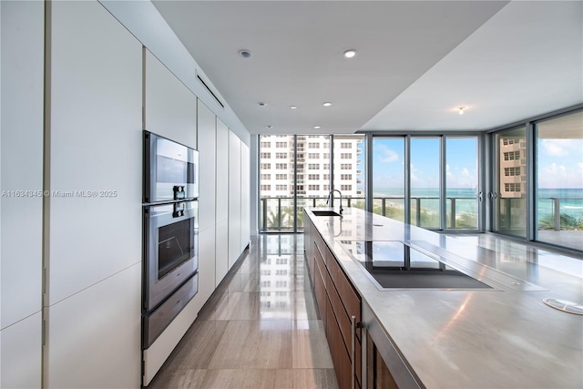 kitchen with black electric cooktop, a wall of windows, a healthy amount of sunlight, and sink