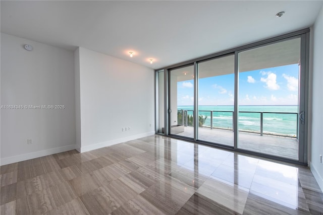 spare room featuring a water view and a wall of windows