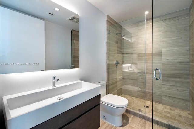 bathroom featuring vanity, an enclosed shower, and toilet