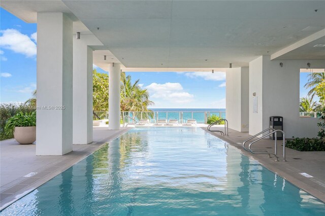 view of swimming pool featuring a water view and a patio