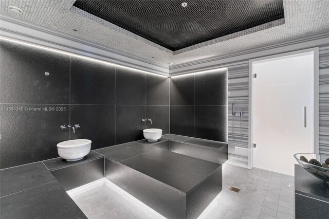 bathroom featuring a raised ceiling and tile walls