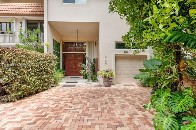 view of exterior entry featuring a garage and stucco siding