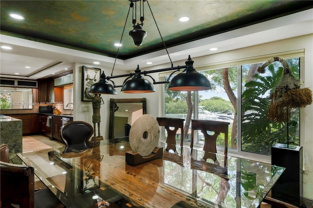 dining space with light wood finished floors and a tray ceiling