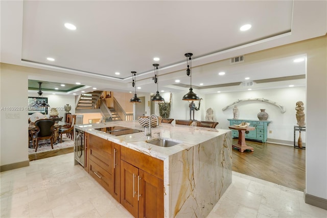 kitchen featuring a sink, a raised ceiling, visible vents, and black electric cooktop