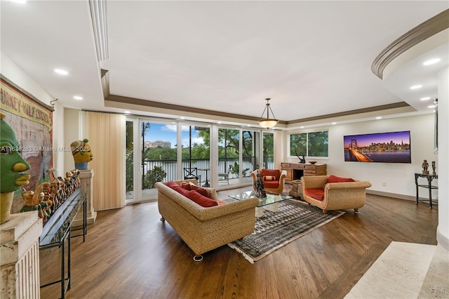 living area with wood finished floors, recessed lighting, a raised ceiling, and baseboards