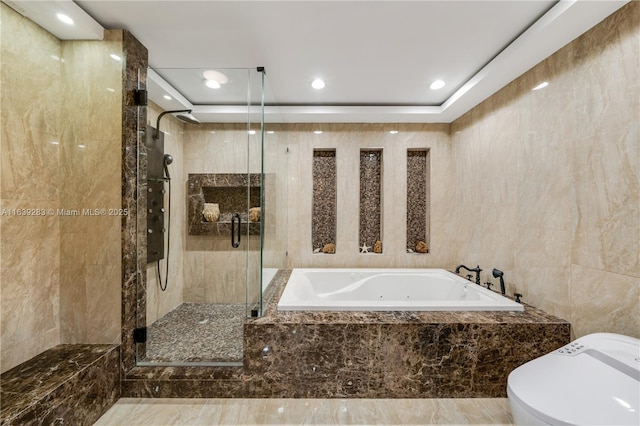 bathroom with tile walls, recessed lighting, toilet, a stall shower, and a jetted tub