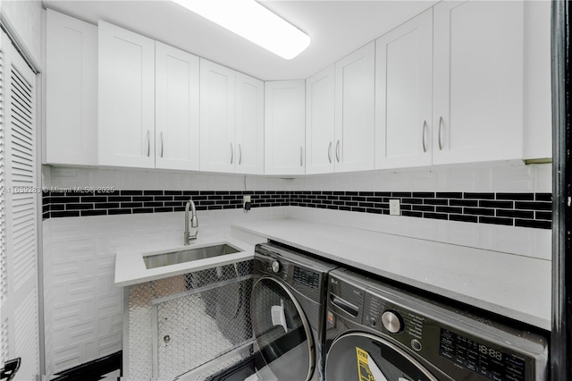 clothes washing area with cabinet space, a sink, and washing machine and clothes dryer