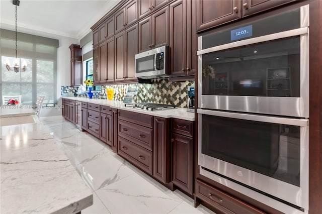 kitchen featuring pendant lighting, an inviting chandelier, crown molding, appliances with stainless steel finishes, and light stone counters