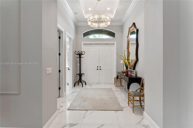 foyer with a chandelier, a raised ceiling, and crown molding