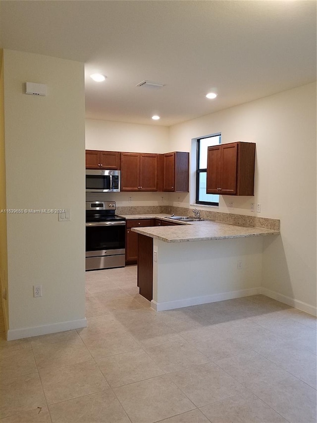 kitchen featuring light tile patterned floors, appliances with stainless steel finishes, a kitchen breakfast bar, sink, and kitchen peninsula