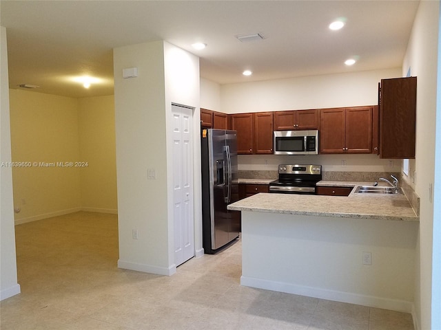 kitchen featuring light tile patterned floors, appliances with stainless steel finishes, sink, and kitchen peninsula