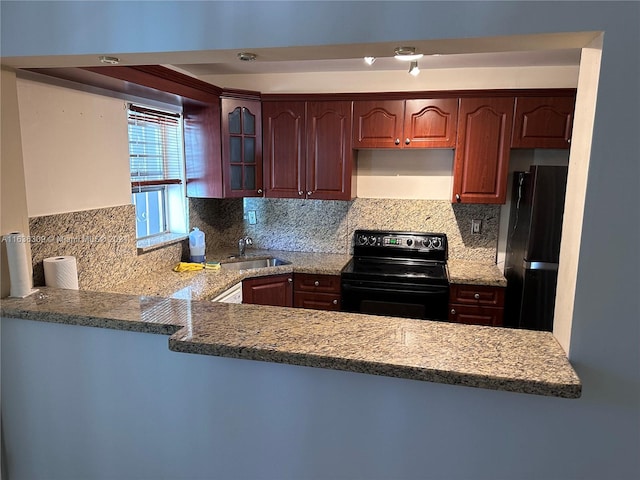 kitchen featuring electric range, tasteful backsplash, black refrigerator, and kitchen peninsula