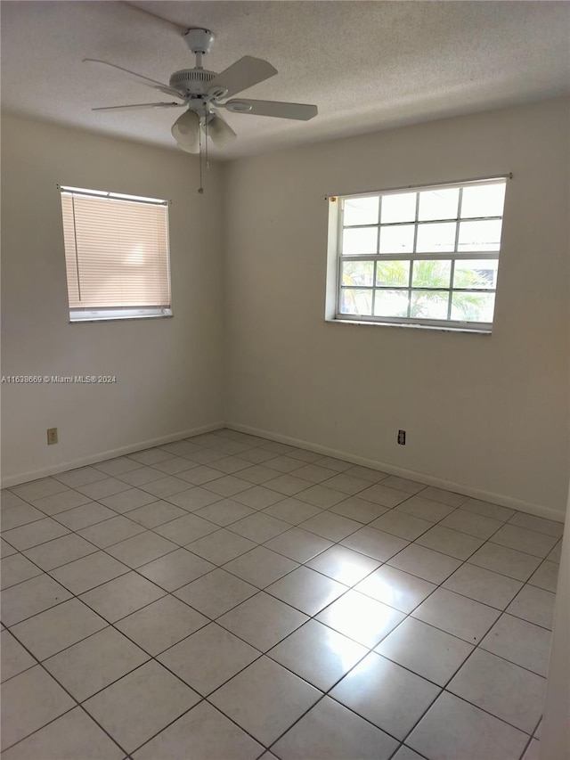 empty room with light tile patterned floors, a textured ceiling, and ceiling fan