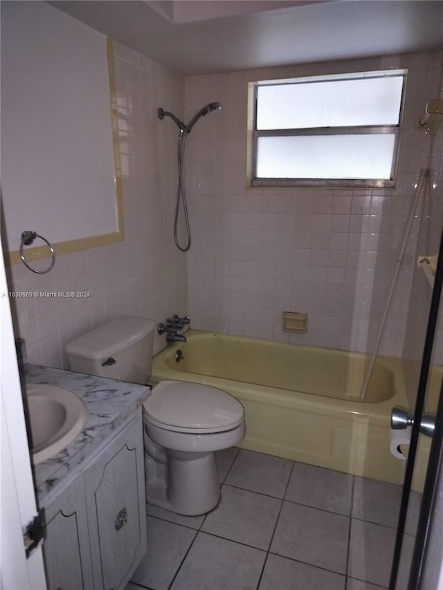 full bathroom featuring tile patterned floors, vanity, tiled shower / bath combo, and tile walls