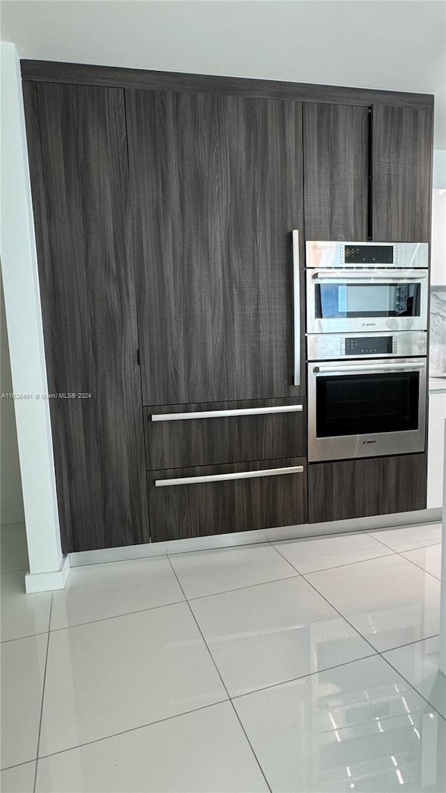 kitchen featuring dark brown cabinets, stainless steel double oven, and light tile patterned floors