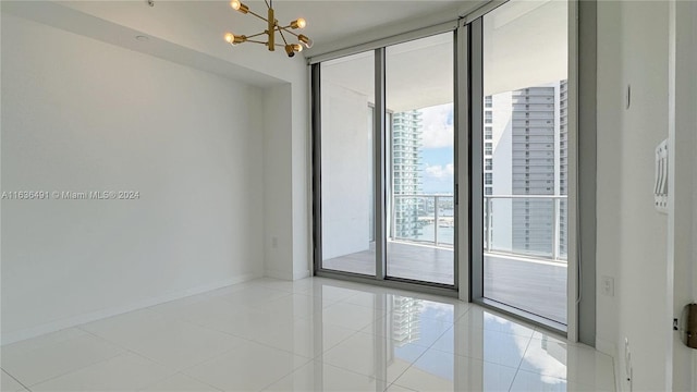 tiled empty room featuring floor to ceiling windows and a notable chandelier