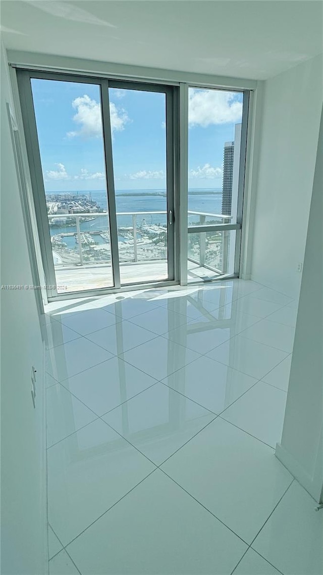 tiled empty room featuring a water view and plenty of natural light