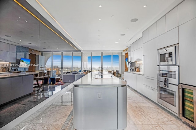 kitchen featuring appliances with stainless steel finishes, beverage cooler, an island with sink, expansive windows, and a wealth of natural light