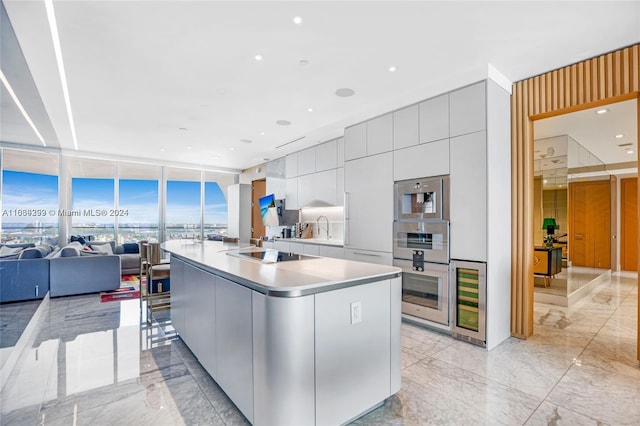 kitchen featuring light tile patterned flooring, a wall of windows, black electric cooktop, and a kitchen island with sink