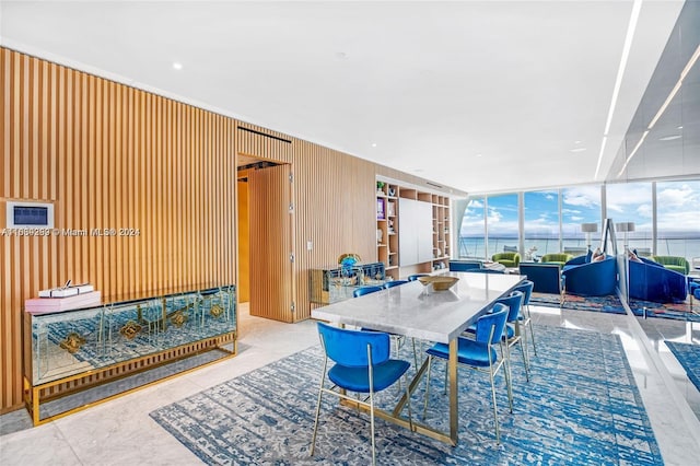 tiled dining area featuring a water view and a wall of windows