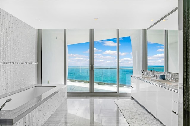 bathroom with a water view, vanity, tiled tub, and tile patterned flooring