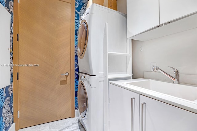 laundry room featuring cabinets, stacked washer / dryer, sink, and tile patterned floors