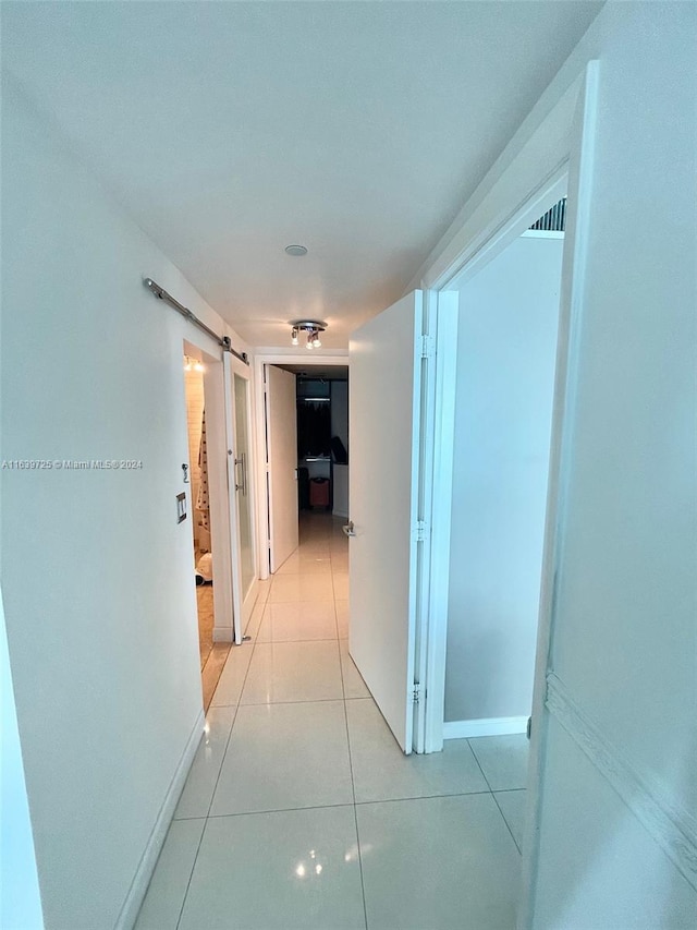 corridor with a barn door and light tile patterned floors