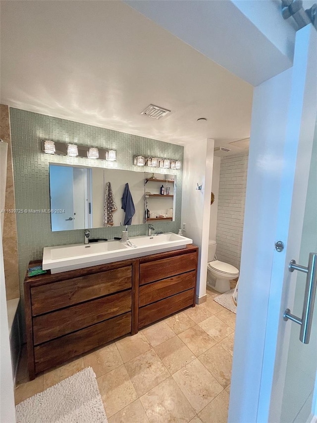 bathroom with dual bowl vanity, tile patterned floors, and toilet