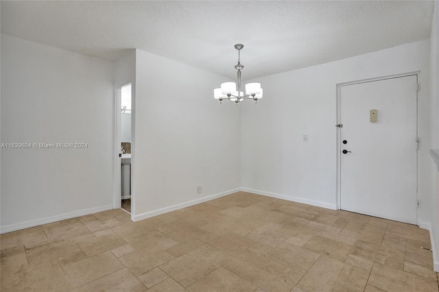 unfurnished room featuring a notable chandelier and a textured ceiling