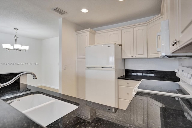 kitchen featuring sink, white appliances, dark stone countertops, hanging light fixtures, and a chandelier