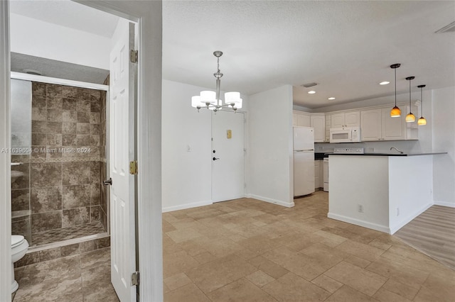 kitchen featuring white appliances, white cabinetry, hanging light fixtures, an inviting chandelier, and kitchen peninsula