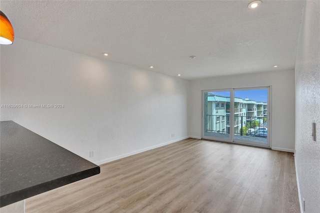 spare room with a textured ceiling and light wood-type flooring