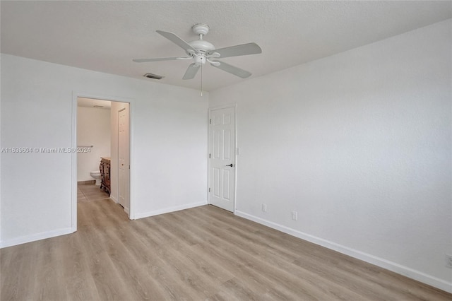 empty room with ceiling fan, a textured ceiling, and light wood-type flooring