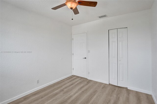 unfurnished bedroom with light hardwood / wood-style floors, a closet, and ceiling fan