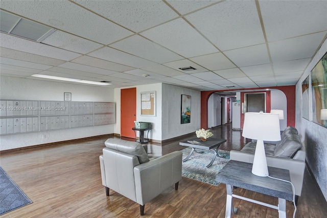 living room featuring hardwood / wood-style flooring, mail boxes, and a drop ceiling